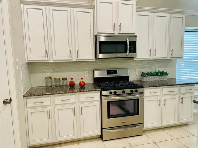 a kitchen with granite countertop white cabinets and stainless steel appliances