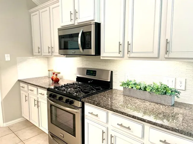a kitchen with granite countertop stainless steel appliances a stove a microwave and cabinets
