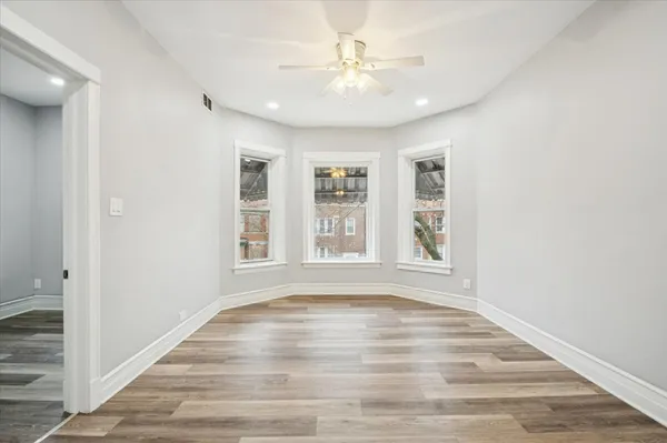 a view of an empty room with a window and wooden floor