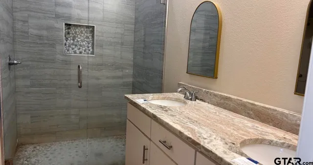 a bathroom with a granite countertop sink a mirror and shower