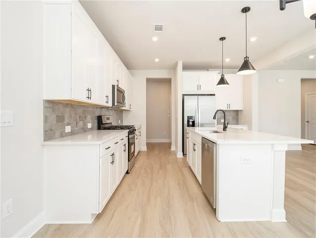 a kitchen with kitchen island granite countertop a sink a counter top space stainless steel appliances and cabinets