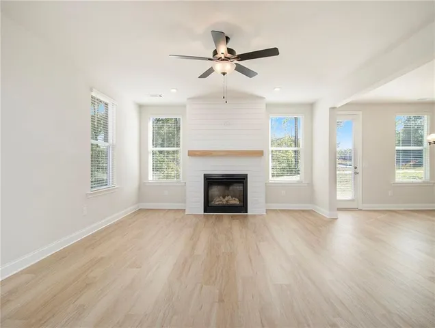 a view of an empty room with wooden floor fireplace and a window