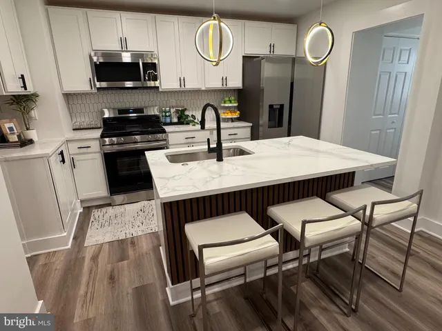 a kitchen with granite countertop a stove a sink dishwasher and white cabinets with wooden floor