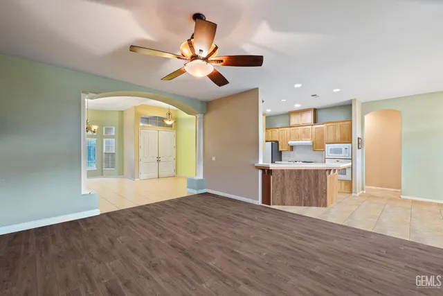 a view of an empty room with wooden floor and a kitchen