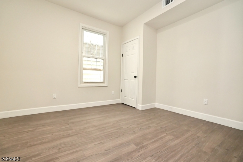 282 Woodside Avenue, Unit 1 Newark, NJ 07104 - Photo 12 of 18 an empty room with wooden floor and window