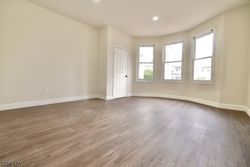 282 Woodside Avenue, Unit 1 Newark, NJ 07104 - Photo 8 of 18 an empty room with wooden floor and windows