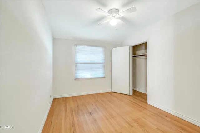 an empty room with wooden floor and fan