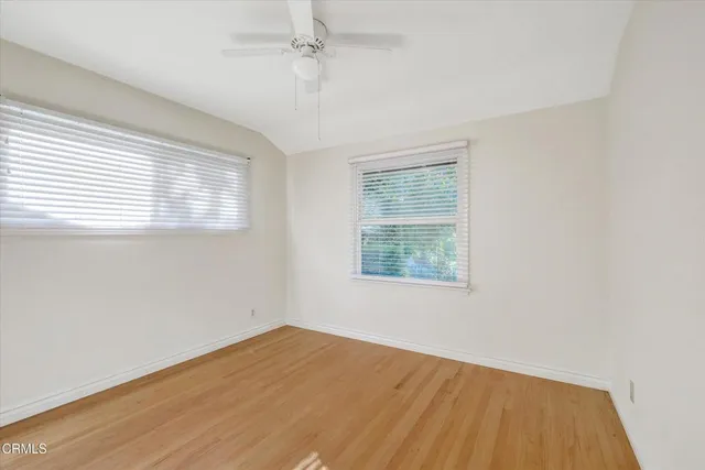 a view of empty room with wooden floor and fan
