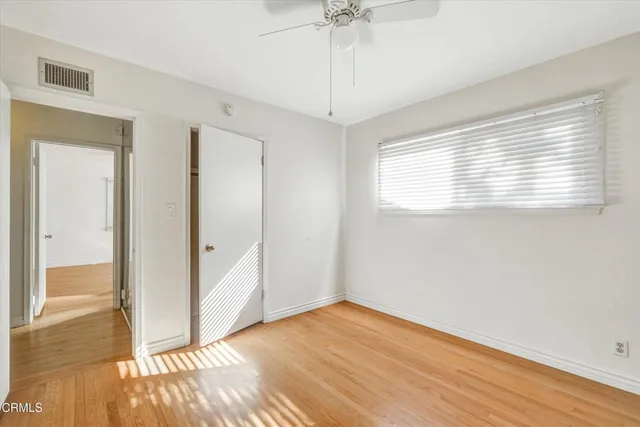 a view of empty room with wooden floor and fan