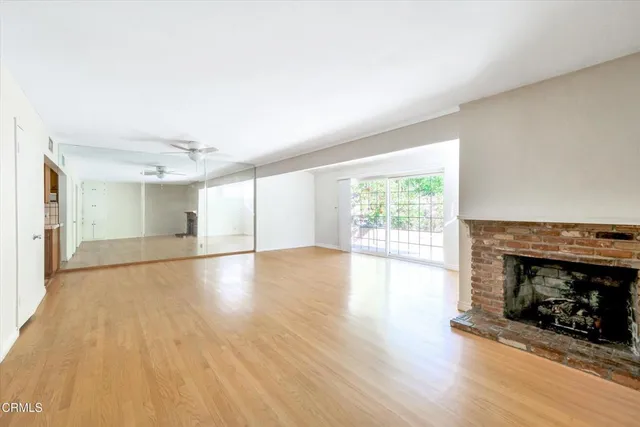 a view of empty room with wooden floor and ceiling fan