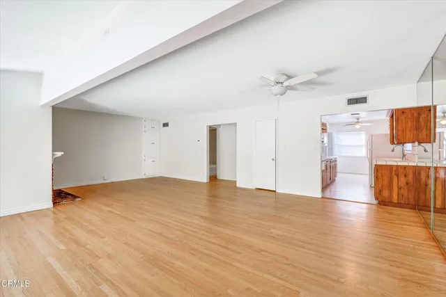 a view of empty room with wooden floor and fan