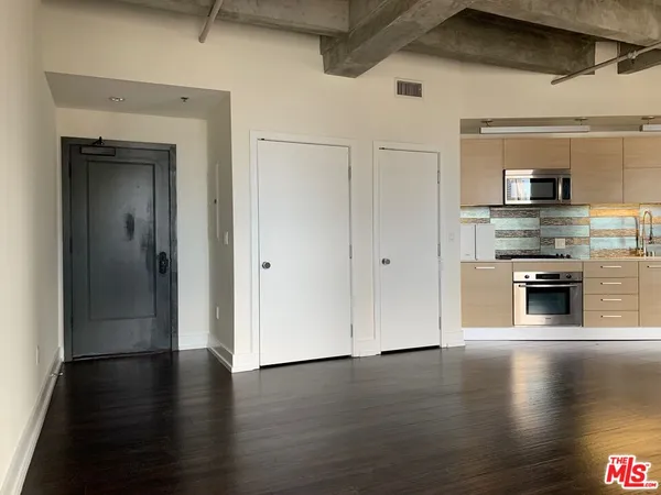 a view of a livingroom with wooden floor and a kitchen