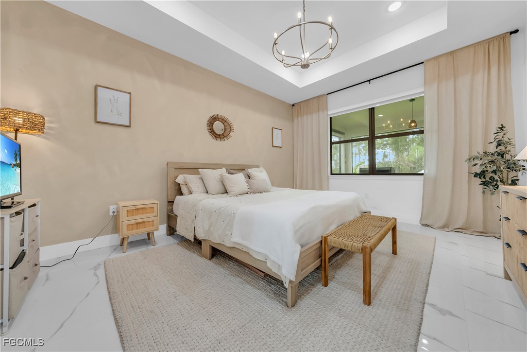 2609 27th Street West Lehigh Acres, FL 33971 - Photo 13 of 35 a bedroom with a bed and a chandelier