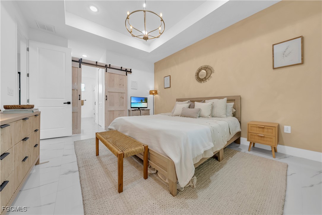 2609 27th Street West Lehigh Acres, FL 33971 - Photo 14 of 35 a spacious bedroom with a bed and a chandelier