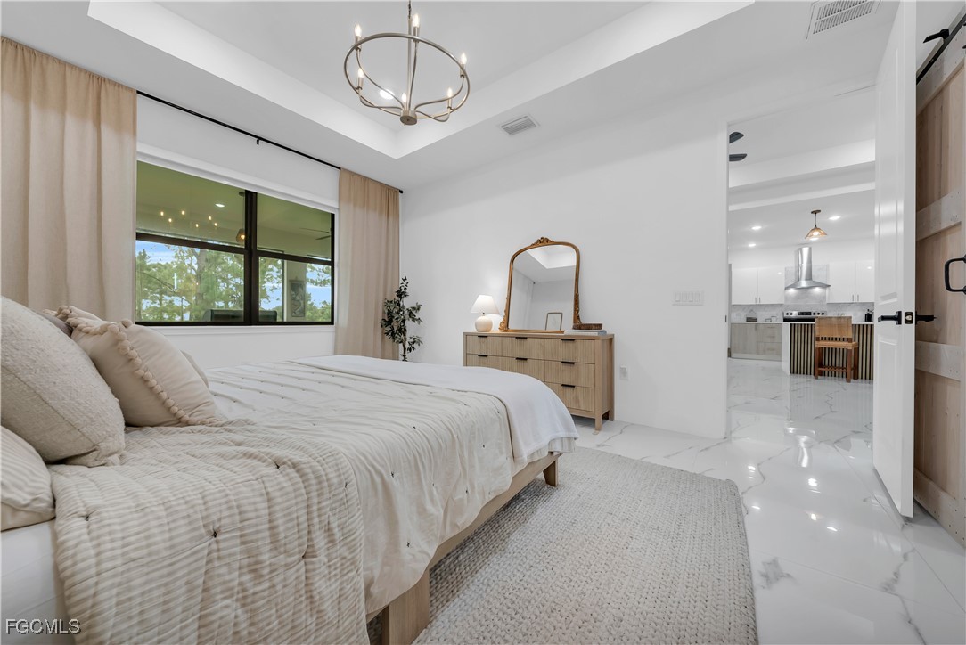 2609 27th Street West Lehigh Acres, FL 33971 - Photo 15 of 35 a bedroom with a large bed and a chandelier