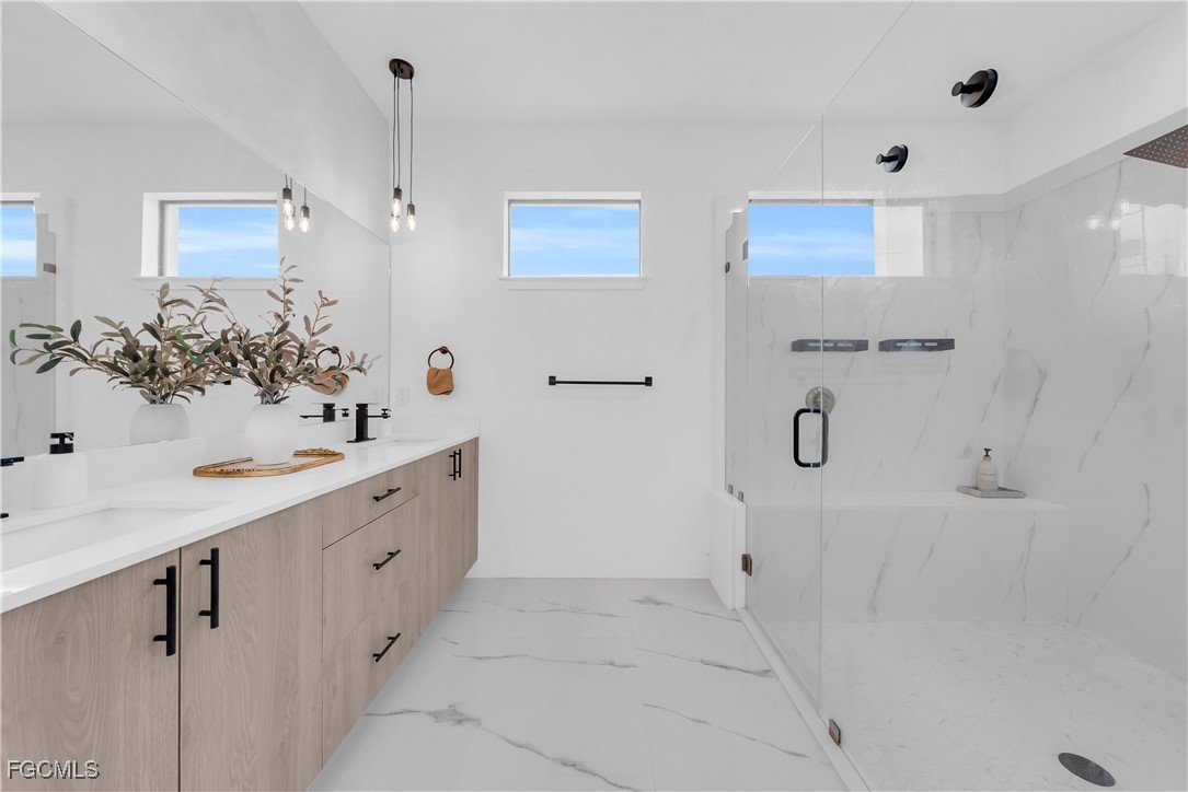 2609 27th Street West Lehigh Acres, FL 33971 - Photo 16 of 35 a bathroom with a double vanity sink a mirror and shower