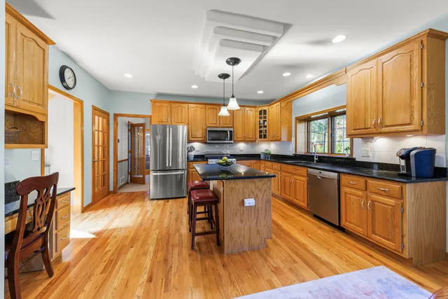 a kitchen with stainless steel appliances granite countertop wooden cabinets a refrigerator a stove a sink and dishwasher a oven with wooden floor