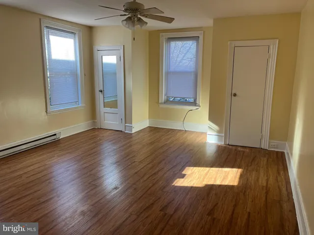 a view of empty room with wooden floor and fan
