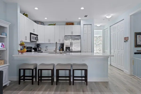 a kitchen with stainless steel appliances granite countertop a table chairs sink refrigerator and cabinets