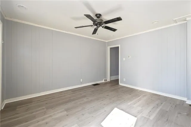 an empty room with wooden floor and ceiling fan