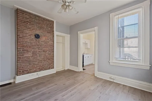 an empty room with wooden floor chandelier fan and windows