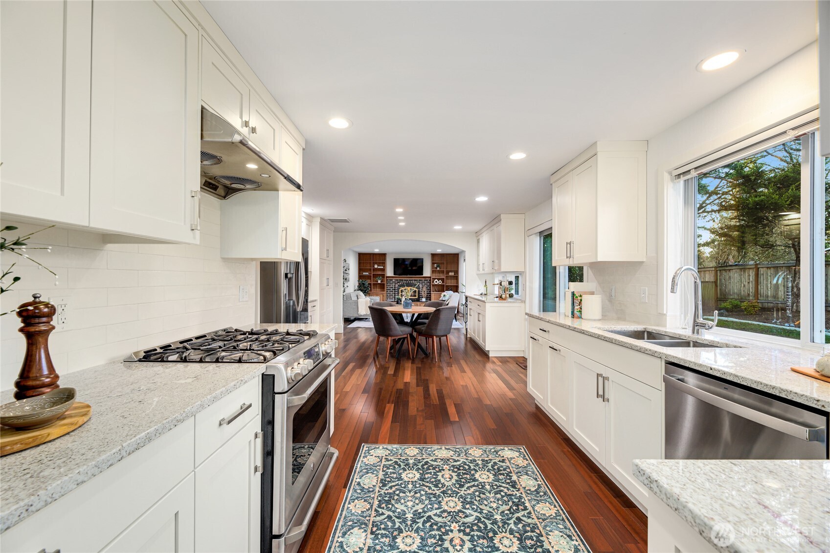 6116 152nd Avenue Northeast Redmond, WA 98052 - Photo 9 of 34 a kitchen with granite countertop a stove top oven a sink dishwasher and white cabinets with wooden floor