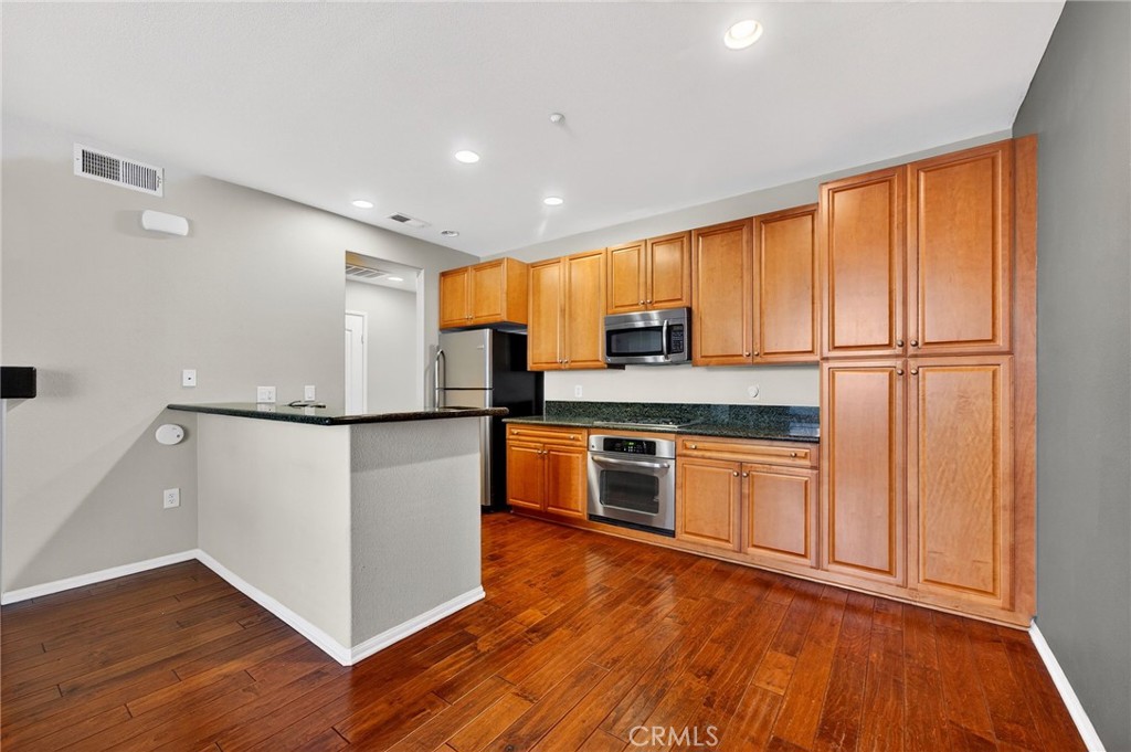 30505 Canyon Hills Road, Unit 1903 Lake Elsinore, CA 92532 - Photo 7 of 36 a kitchen with stainless steel appliances granite countertop a refrigerator a stove a sink and a microwave with wooden floor