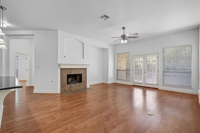 a view of an empty room with a fireplace and wooden floor