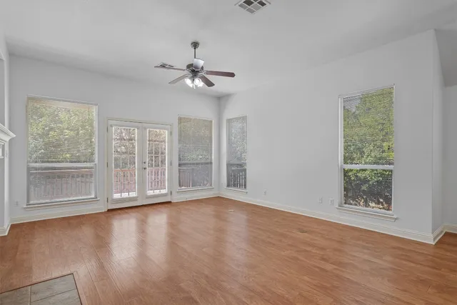 a view of an empty room with a window and wooden floor