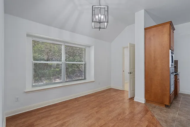 an empty room with wooden floor closet and windows