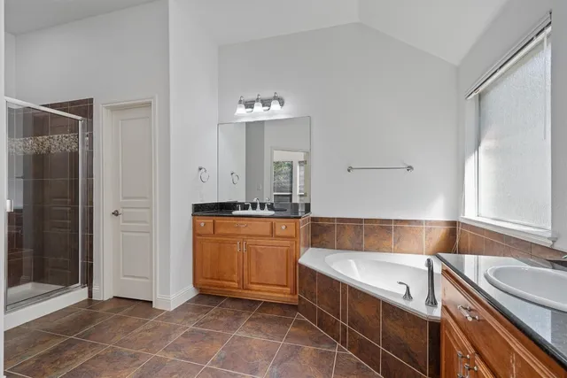 a bathroom with a granite countertop sink and a bathtub