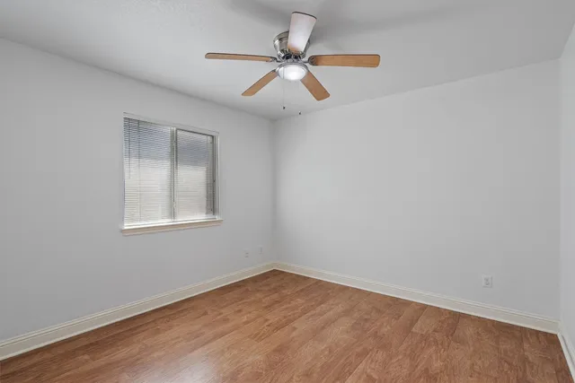 an empty room with a window and a fan