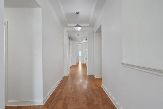 a view of a hallway with wooden floor and a ceiling fan