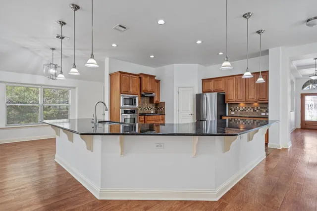 a large kitchen with stainless steel appliances kitchen island a large counter top and a wooden floor