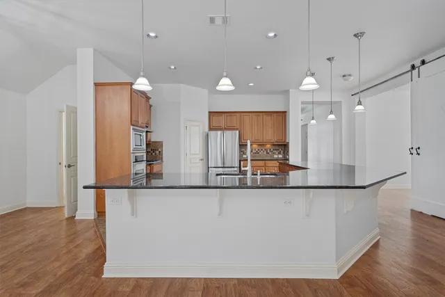 a large kitchen with a large counter top space a sink appliances and cabinets