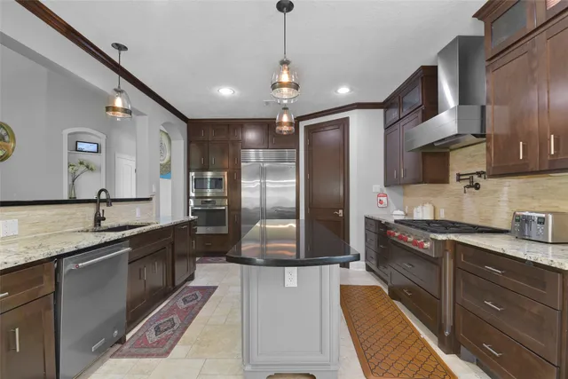 a large kitchen with stainless steel appliances kitchen island granite countertop a refrigerator a sink a stove and dishwasher