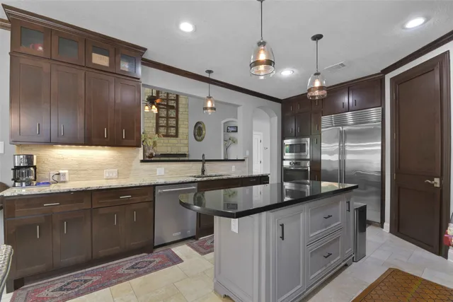 a kitchen with kitchen island granite countertop stainless steel appliances lots of counter space sink and refrigerator
