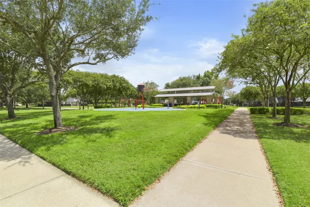 a view of a big house with a big yard plants and large trees