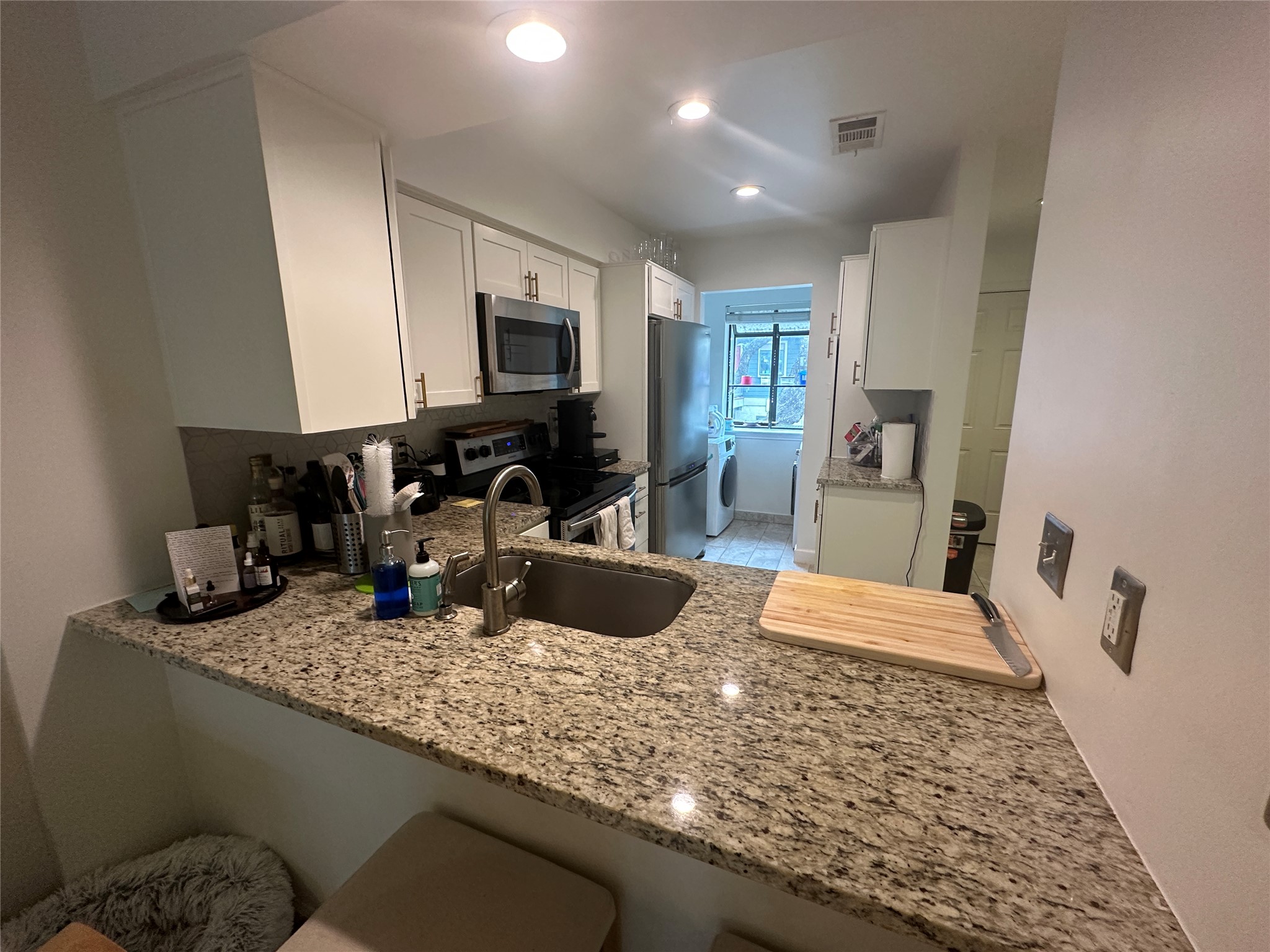 2215 Post Road, Unit 2002 Austin, TX 78704 - Photo 4 of 12 a kitchen with sink a microwave a refrigerator and cabinets