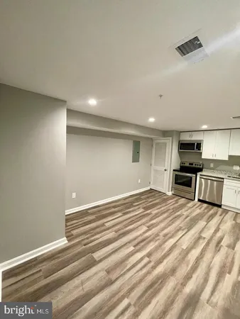 a view of kitchen with stainless steel appliances cabinets and empty room