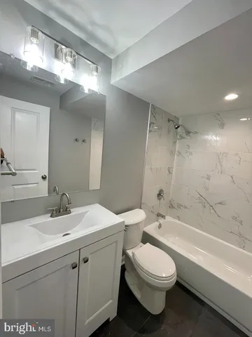 a bathroom with a sink a toilet a mirror and bathtub