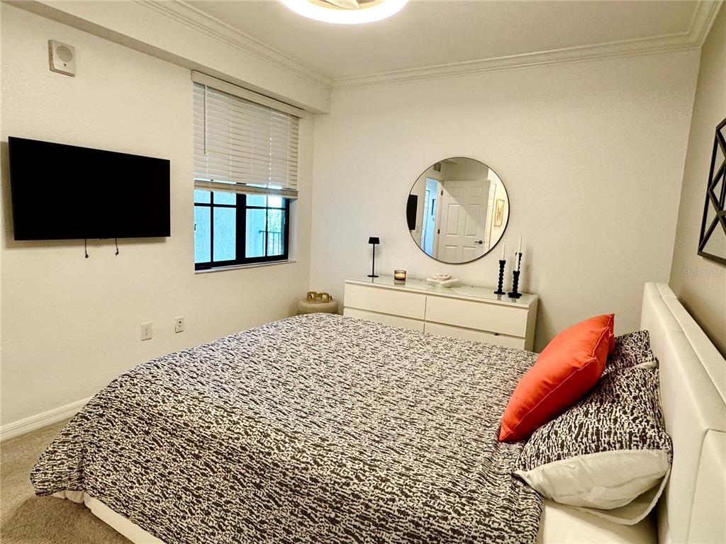 18028 Gawthrop Drive, Unit 303 Bradenton, FL 34211 - Photo 26 of 58 a bedroom with a bed and a flat screen tv