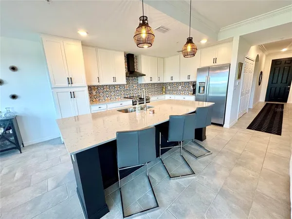 a kitchen with stainless steel appliances kitchen island granite countertop a sink dishwasher a refrigerator and a stove with wooden floor