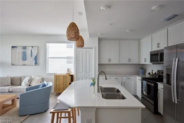 a kitchen with stainless steel appliances a stove a sink a microwave a refrigerator a stove and white cabinets