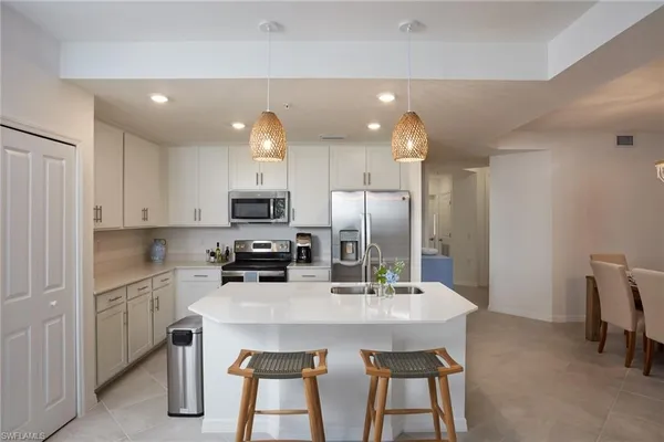 a kitchen with refrigerator a sink and chairs