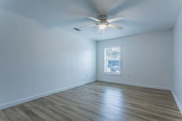 a view of an empty room with wooden floor and a window