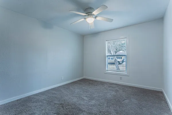an empty room with windows and fan