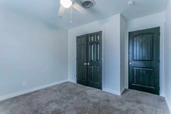 an empty room with closet and a chandelier fan