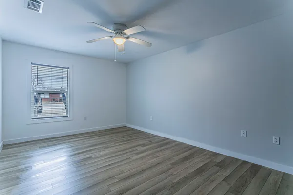 an empty room with wooden floor and windows