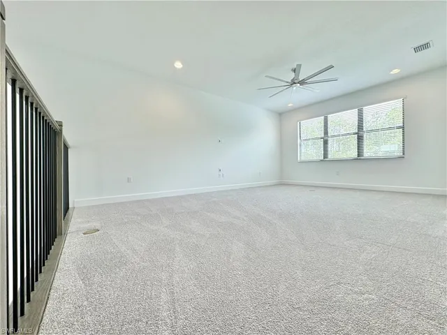 an empty room with chandelier fan and windows